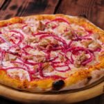 pizza with tuna and red onion on wooden cutting board